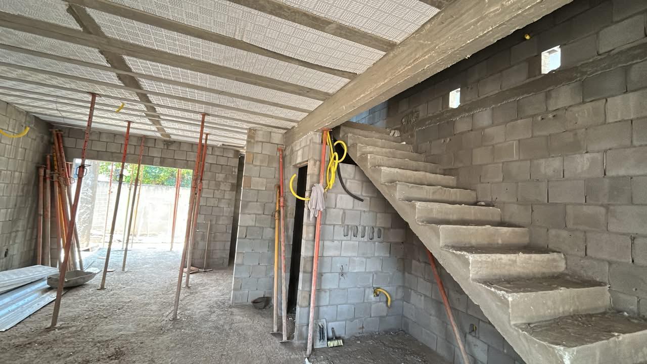 Interior de sobrado em execução, com laje escorada e escada de concreto